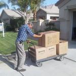 Paul Hoersting pushing a flatbed dolly up the driveway full of boxes.